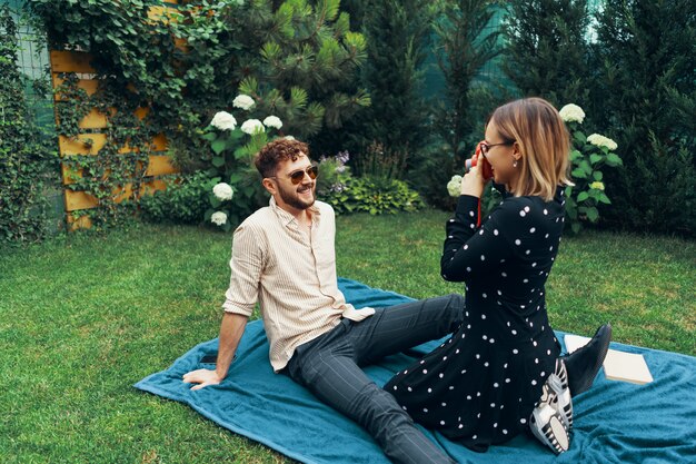 A split image featuring two different celebrity couples. On one side, a glamorous couple is shown at a red carpet event, while the other side portrays a more casual couple enjoying a picnic in a park.