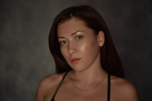 Close-up portrait of a young actress with a determined expression, natural makeup, and slightly tousled hair, lit with soft, flattering light.